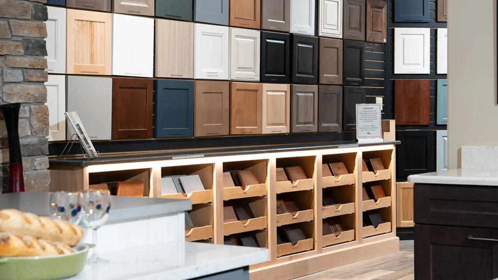 Showroom display wall featuring diverse commercial kitchen cabinet door samples in Shaker style, veneer, and painted MDF.