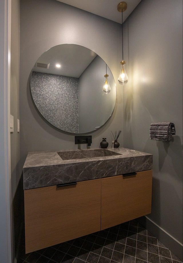 Floating wood bathroom vanity with stone basin surface and round mirror