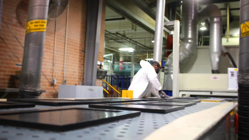 Factory worker inspecting gloss finish on black shaker cabinet doors on a controlled manufacturing assembly line.