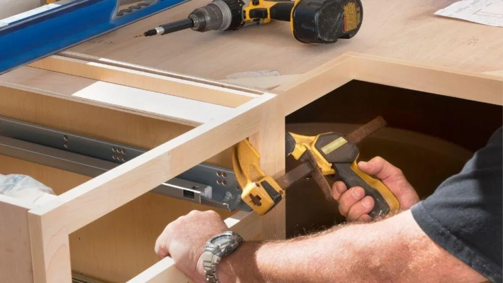 Using a yellow bar clamp to align light wood cabinet face frames for a seamless look against uneven villa walls.